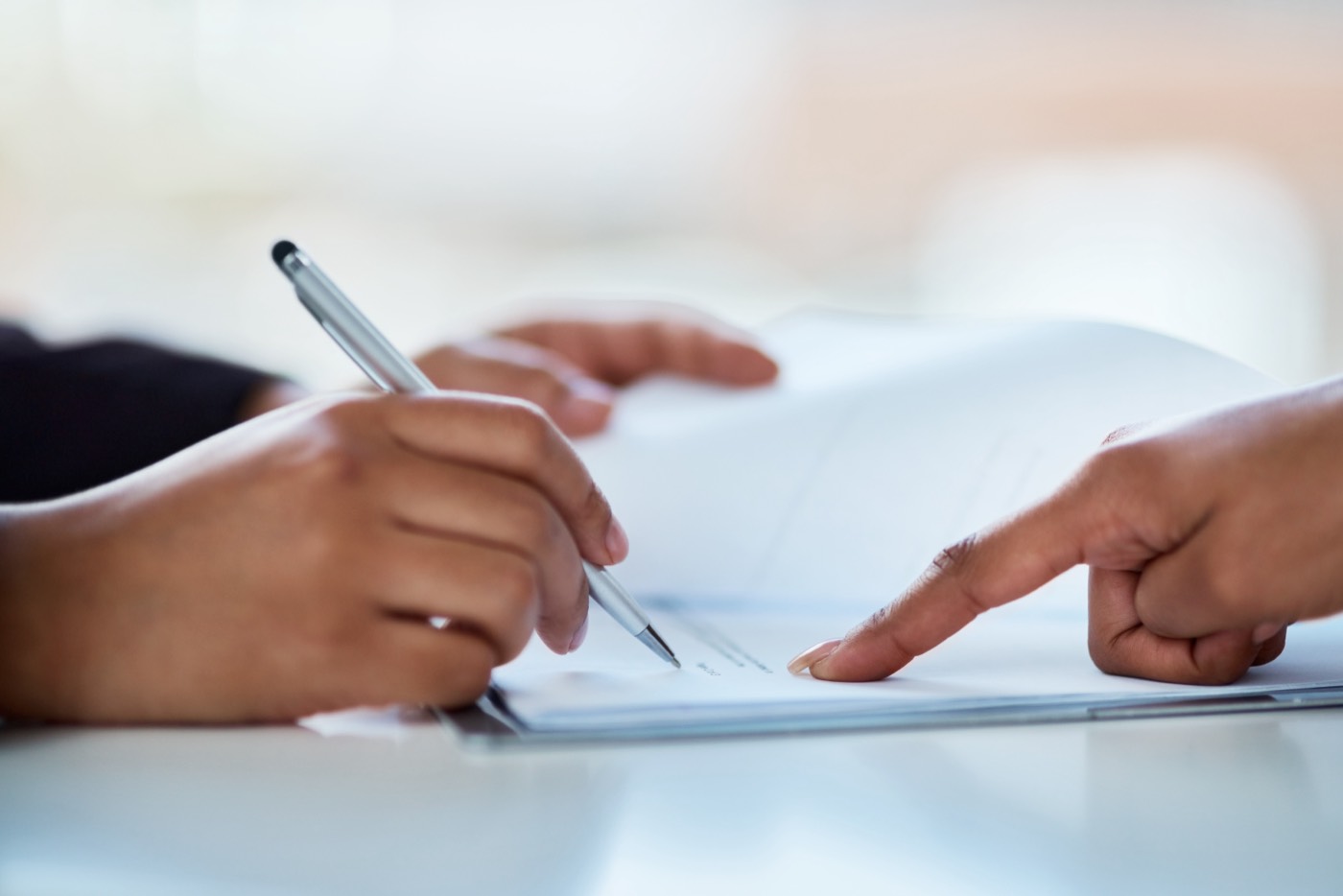 Two colleagues reviewing and signing a document together at a desk