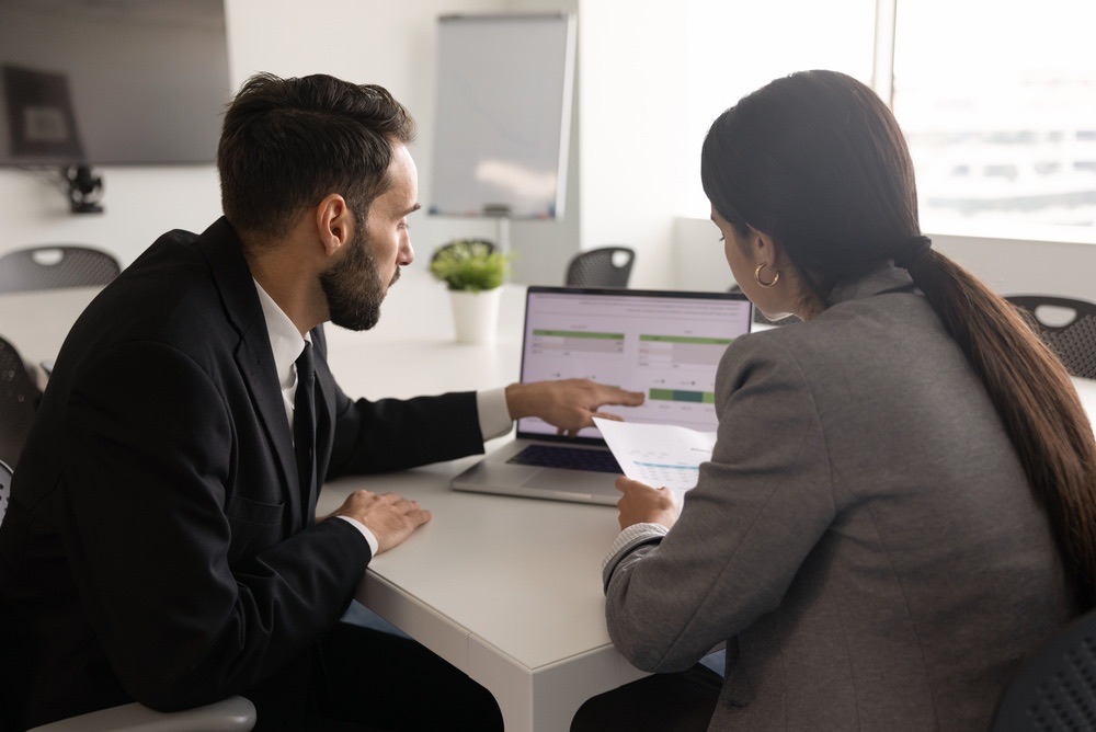 Two colleagues comparing pay run figures on a laptop